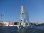 Drei durchl�cherte st�hlerne Menschen stehen hier in der Spree.